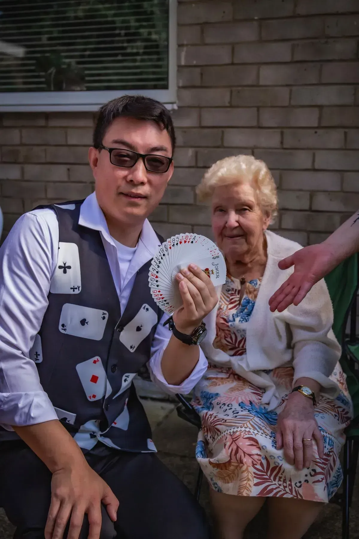 Magic Yin performing a card trick for an older guest at a community event