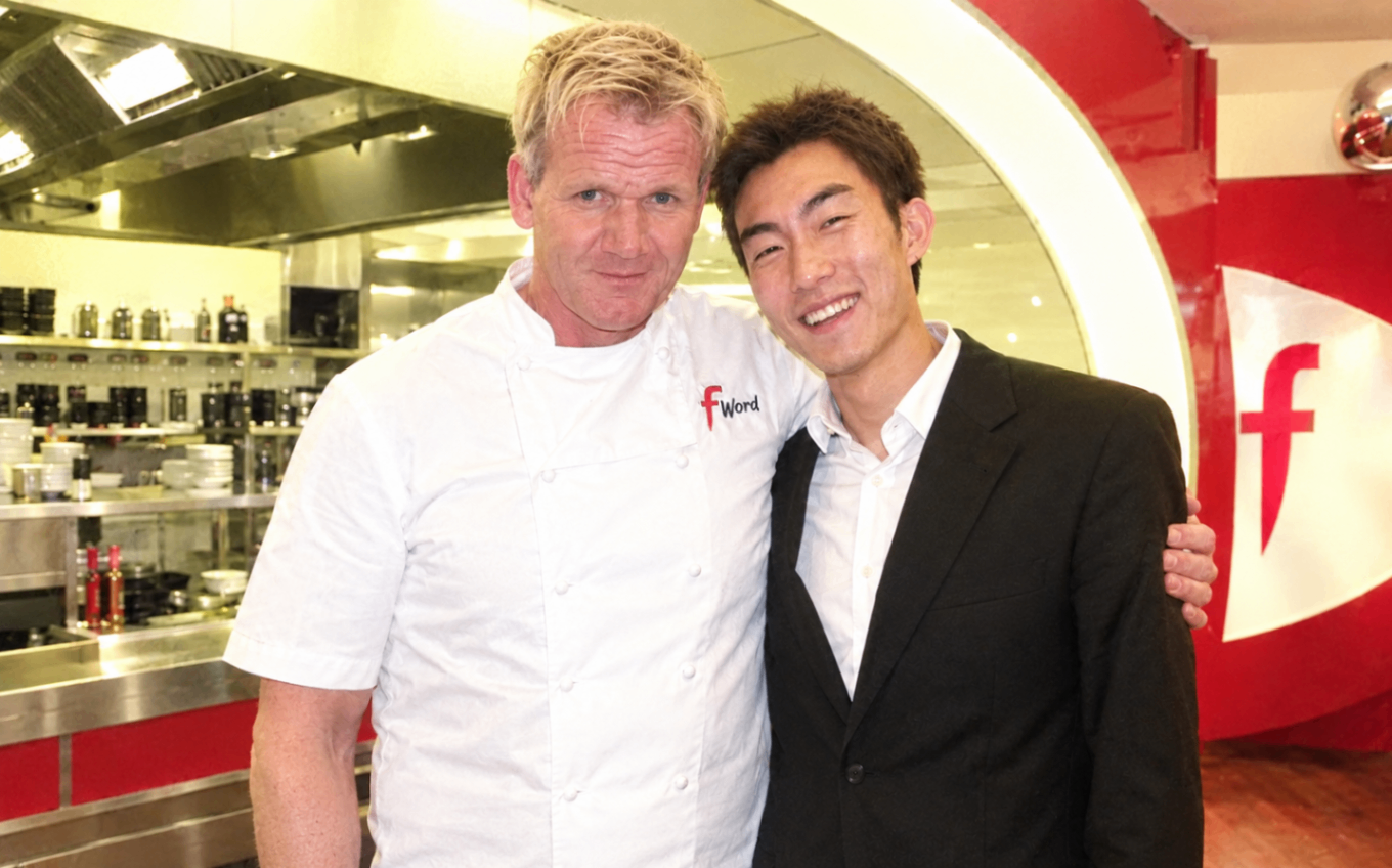 Magic Yin standing beside chef Gordon Ramsay in a professional kitchen